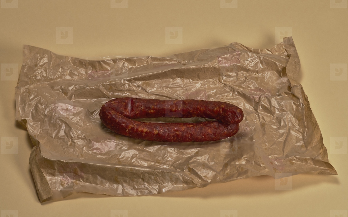 Still life of raw beef sausage on top of wrinkled butcher paper