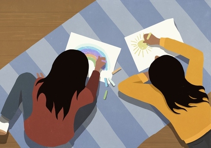 View from above of girls laying on rug and drawing pictures
