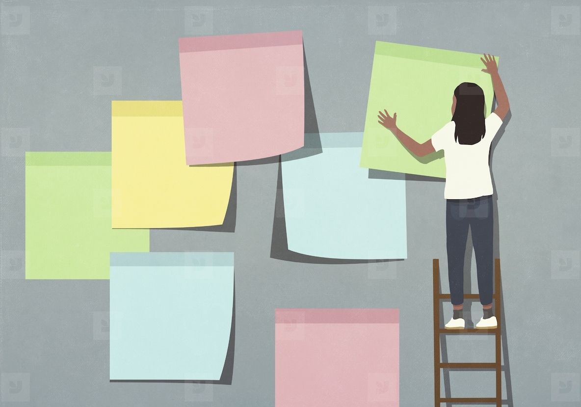 Woman on ladder placing large multicolored adhesive notes