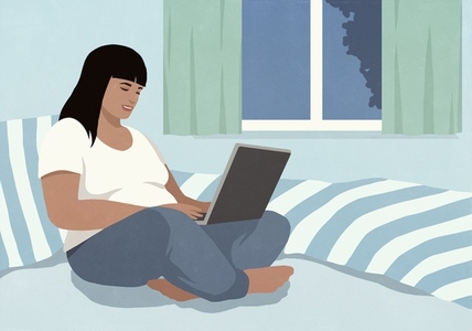 Woman relaxing on bed at night using laptop