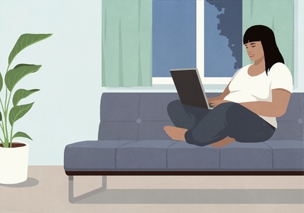 Smiling woman using laptop sitting cross legged