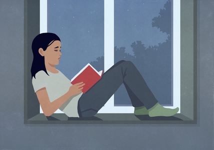 Woman reading book at dark window ledge at night Woman reading book at dark window ledge at night