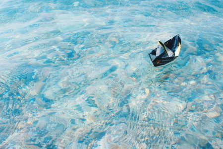 Paper boat sailing on blue water