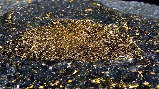 A close up view of a mineral surface featuring shimmering gold