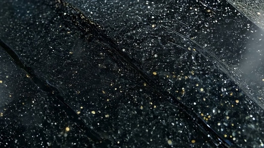 Close up of a shiny black South Onyx surface with water droplets
