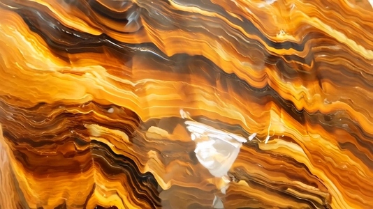 Close up of a polished  wavy patterned brown orange Tigers Eye