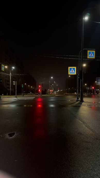 Empty city street at night with wet pavement reflecting lights