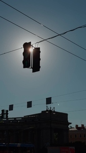 A silhouette of a traffic light against a bright sun in a clear