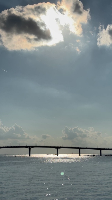 A serene view of a bridge over water under a cloudy sky