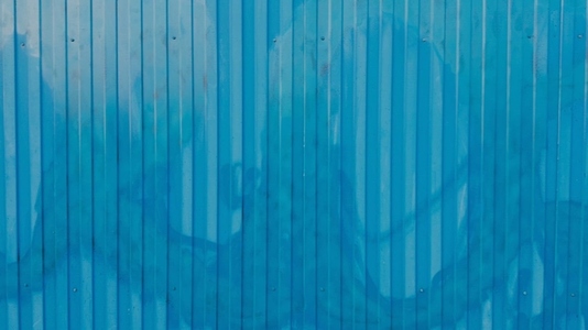 A textured blue metal wall background with vertical lines