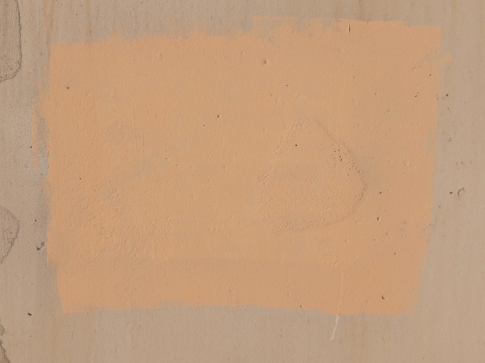 A patch of peach-colored rectangle square paint on a concrete