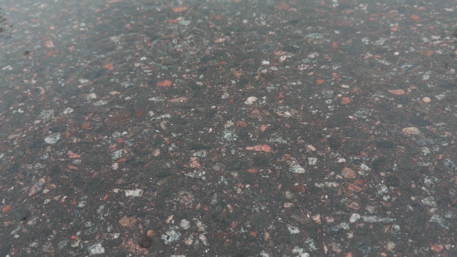 Seamless loop wet asphalt surface with various colored stones