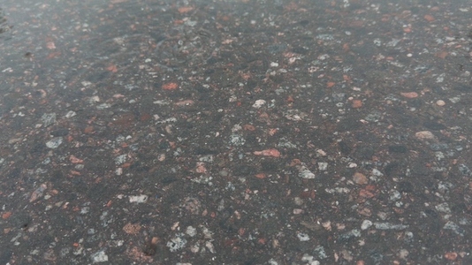 Seamless loop wet asphalt surface with various colored stones